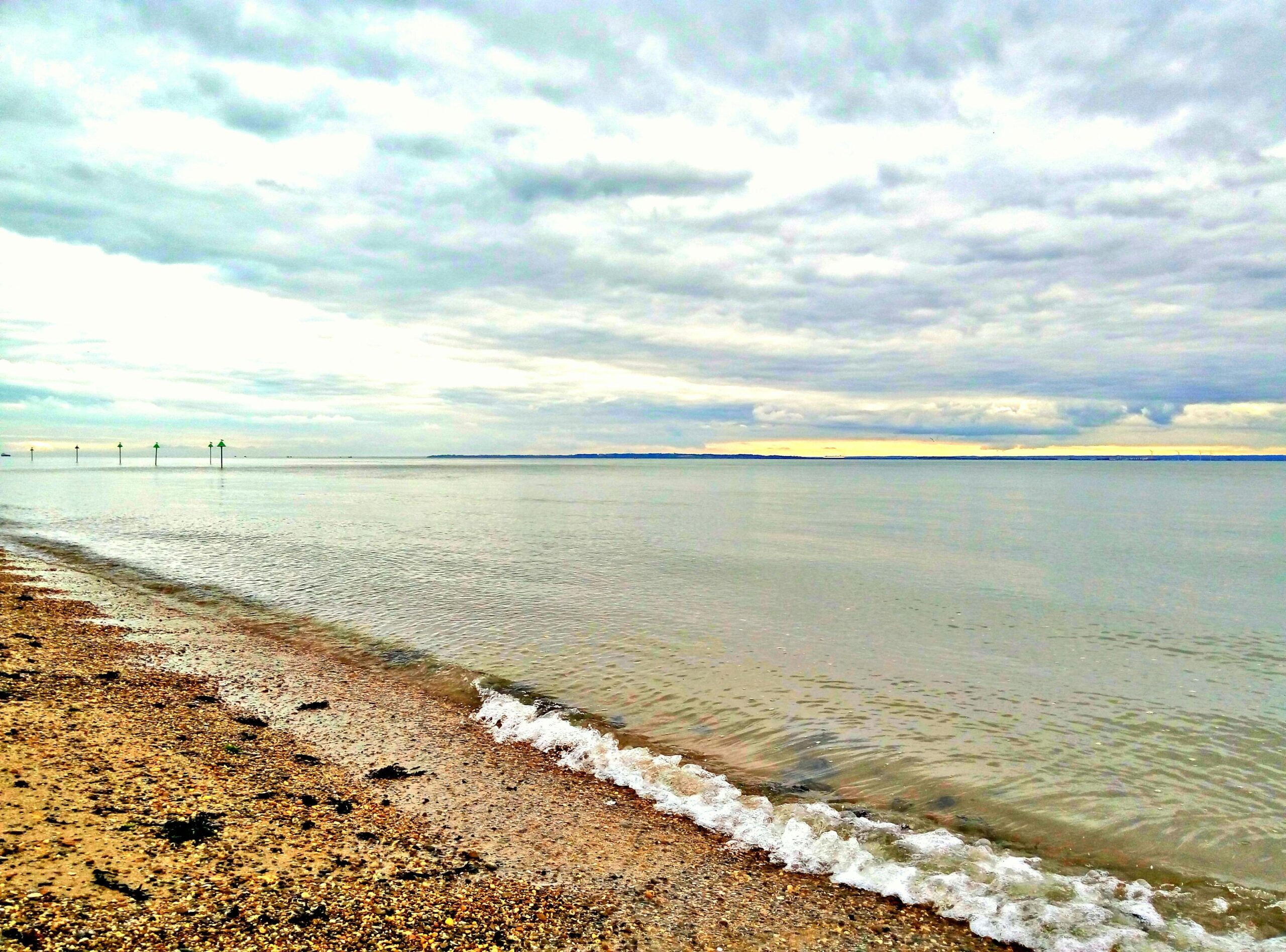 Serene view of a tranquil Southend-on-Sea beach with calm waters and a cloudy sky.